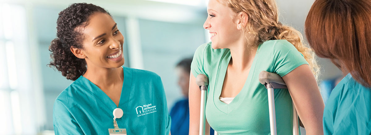 a female on crutches being helped by two female Right at Home caregivers