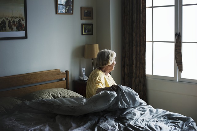 Older woman sitting in bed looking out window