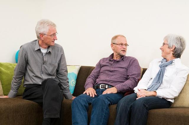 Three family members talking on a couch. Negotiating caregiving with family can help with responsibilities