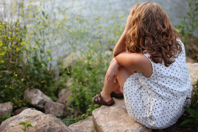 young girl sitting on rock