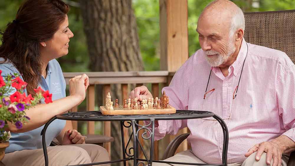 female caregiver playing chess with senior