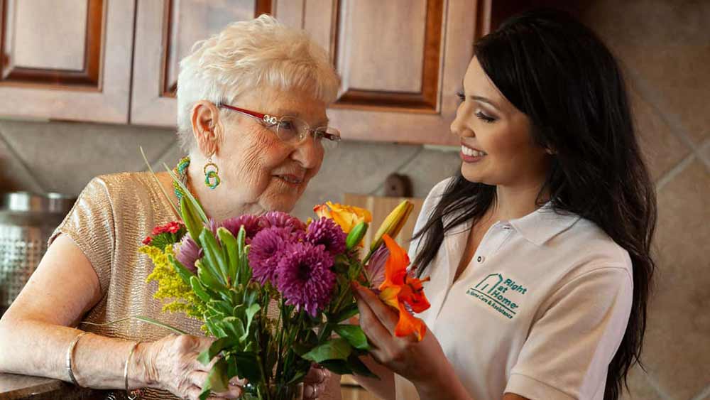 senior and caregiver arranging flowers
