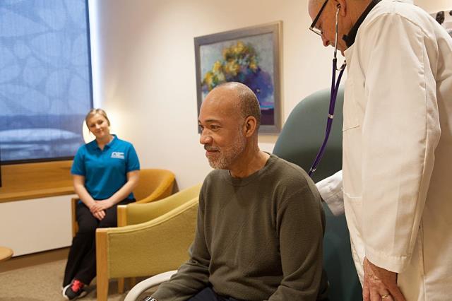 Older man with doctor pressing stethoscope on back