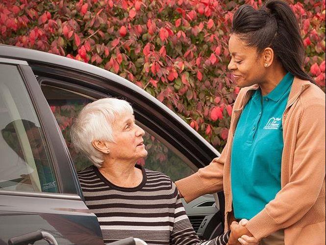 Caregiver helping senior out of car.