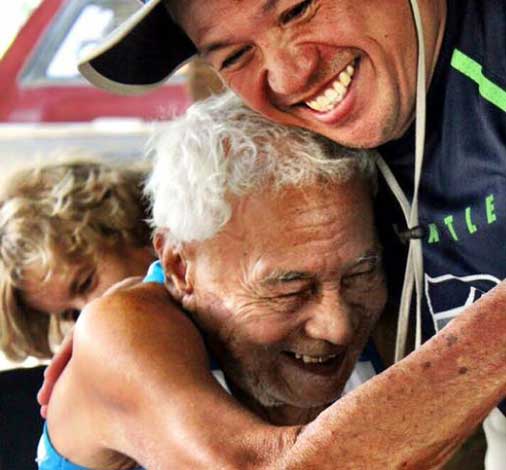 A caregiver hugs a Vietnamese recipient of the Free Wheelchair Mission.