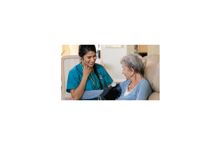 A caregiver takes her client’s blood pressure in a comfortable home.