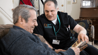 A caregiver is flipping through a book with his client