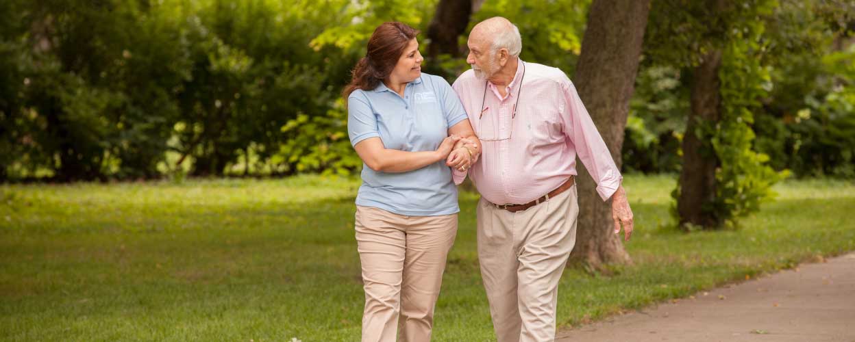 A caregiver walking through a nature scene with her client.