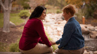 A caregiver and a patient’s family member talk outdoors.