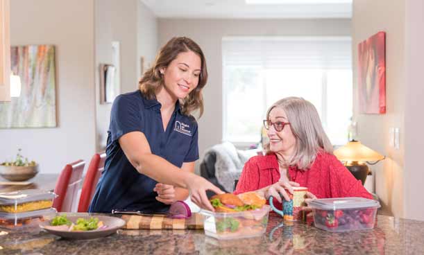 Female caregiver helping a female client prepare her meals for the week.