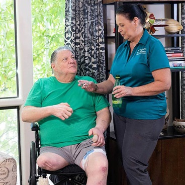 A female caregiver showing a bottle of pills to a female patient.