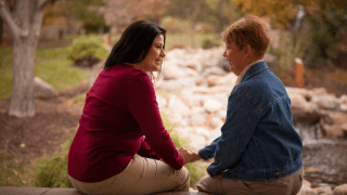 A caregiver and a patient’s family member talk outdoors.