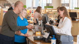 A caregiver and her patient standing in front of a cash register in a store.