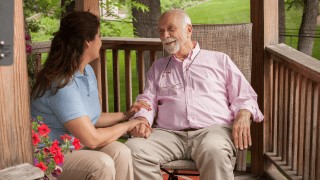 A caregiver comforts a patient sitting in a chair.